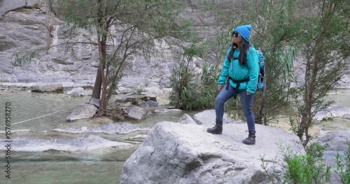 Long shot of mexican woman that walks over a rock  by a pool of blue water