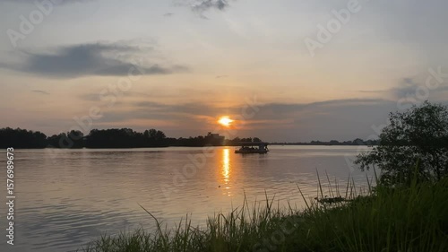 A boat peacefully resting on the water as the sun sets, casting a warm, golden glow across the scene.
