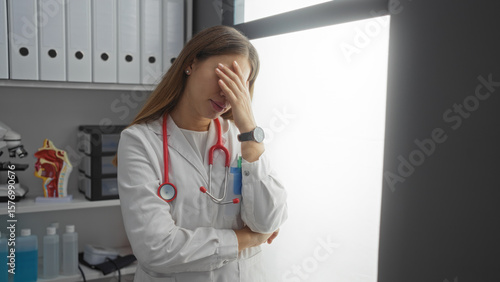 Photos Woman doctor stressed in hospital room with stethoscope and files showing frustration in clinical environment during daytime
