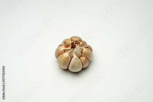 One whole unpeeled garlic clove with its natural white yellowish skin, placed on a clean white background. Perfect for cooking, food photography, or kitchen decoration.