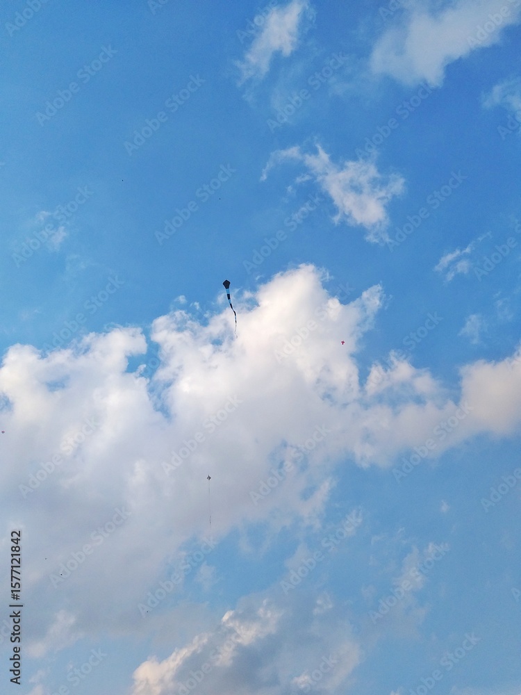 kite flying high in a clear blue sky with scattered clouds – peaceful sky view from the ground perspective kite flying high in a clear blue sky with scattered clouds – peaceful sky view from the ground perspective