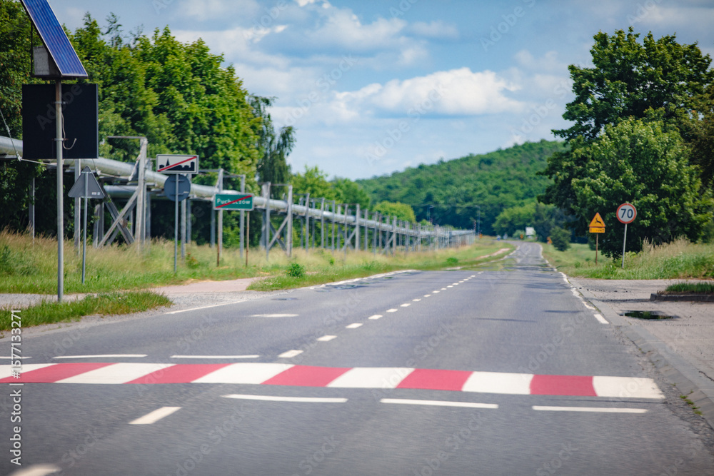Obraz premium A peaceful rural road with a speed bump and traffic signs, highlighting countryside tranquility