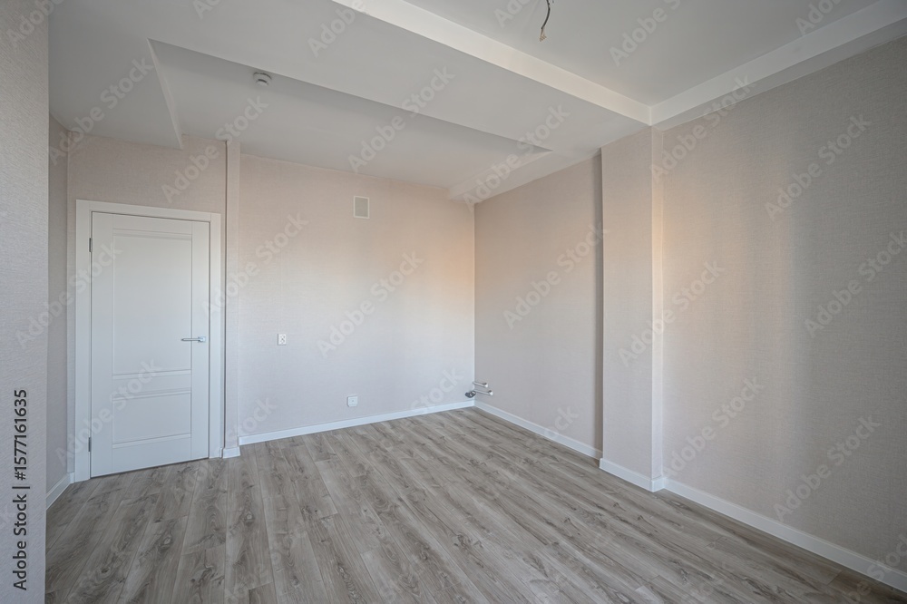 Fototapeta premium empty room with wooden floors, beige walls, a white door, and a complex ceiling design