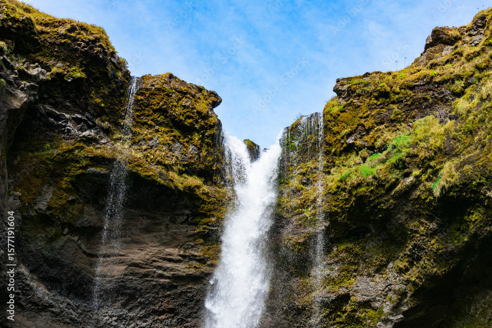 Fototapeta premium Kvernufoss is a hidden waterfall near Skógafoss, reachable through a short, scenic hike. You can even walk behind it for a magical view.