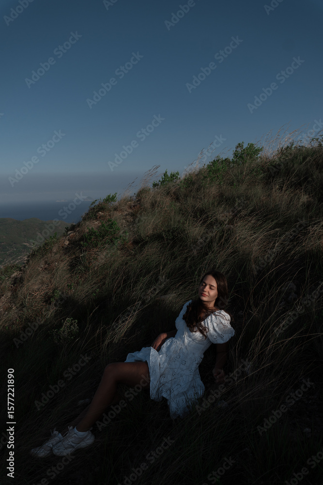 Naklejka premium A beautiful girl in a sarafan walks in the mountains. Wind in her hair.