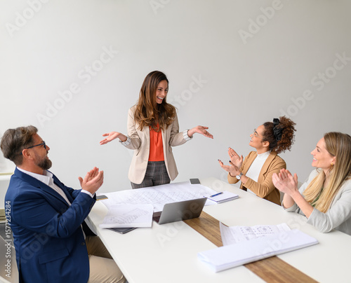 Tableau sur toile Cheerful group of engineers with blueprints and laptop on table applauding for s