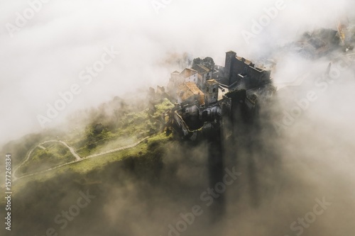 Aerial view of Celleno, a medieval town, perched precariously on a hill, shrouded in ethereal mist, Viterbo, Lazio, Italy.