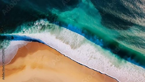 Breathtaking aerial view of ocean waves crashing on a golden beach shoreline