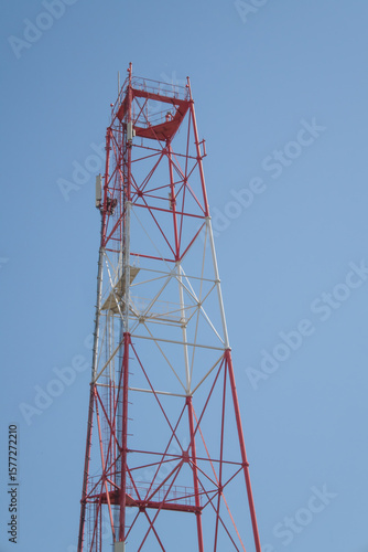 unfinished red and white radio tower against a clear blue sky, radio broadcast