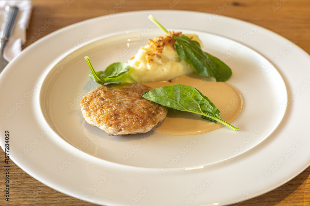 Meat patty, fresh spinach leaves, creamy mashed potatoes, and flavorful sauce on white round plate. Culinary arts, food styling Meat patty, fresh spinach leaves, creamy mashed potatoes, and flavorful sauce on white round plate. Culinary arts, food styling
