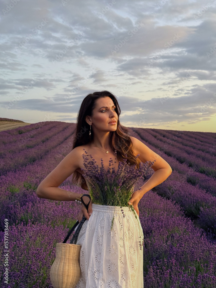 Obraz premium beautiful woman with dark hair in elegant outfit posing in sunset lavender blooming field with accessories
