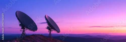 Two large satellite dishes stand on a mountaintop. Scanning the universe for signals against a vibrant sunset backdrop. Hinting at the search for extraterrestrial life and the mysteries of deep space