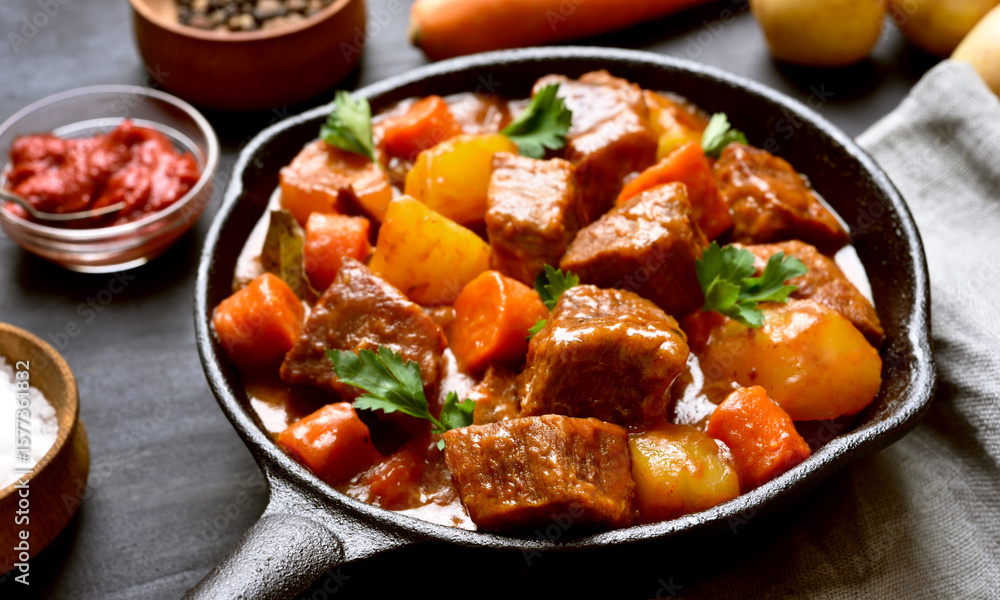 Hearty beef stew simmers in a cast iron pan, a comforting and flavorful meal featuring tender meat, carrots, potatoes, and rich gravy, perfect for a delicious dinner. Hearty beef stew simmers in a cast iron pan, a comforting and flavorful meal featuring tender meat, carrots, potatoes, and rich gravy, perfect for a delicious dinner.