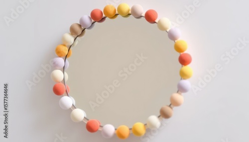 Round mirror decorated with colorful balls on a white background