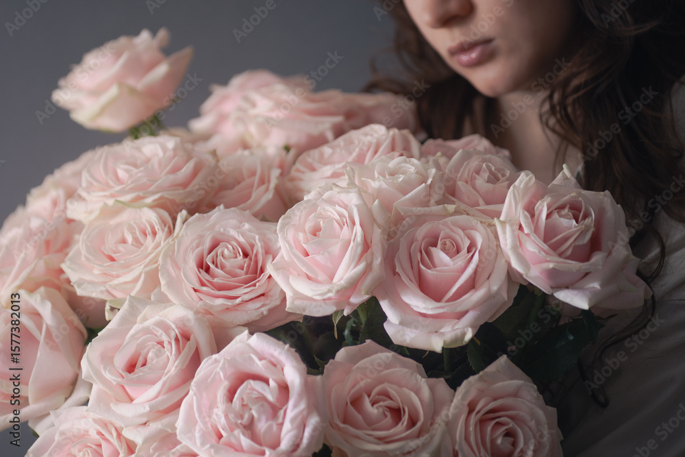 Fototapeta premium young woman holding a large beautiful bouquet of roses, online flower shop, fresh cut flowers delivery