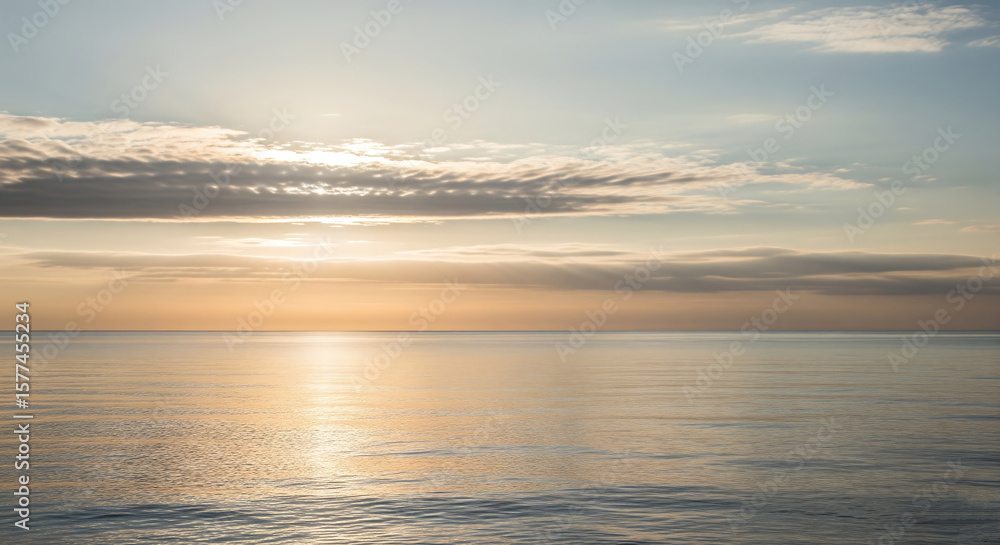 Fototapeta premium Sunlight breaks through clouds over the tranquil ocean at dawn