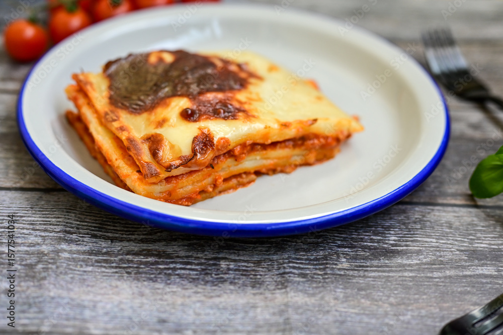 Delicious Home made Lasagna with minced meat,tomato sauce and spinach on a wooden rustic background.Home made italian meal Delicious Home made Lasagna with minced meat,tomato sauce and spinach on a wooden rustic background.Home made italian meal