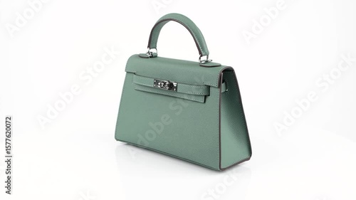 High-quality 360° video of a teal leather shoulder bag with clasp rotating on a white background. Ideal for product display, online store, or stylish fashion content in 4K.