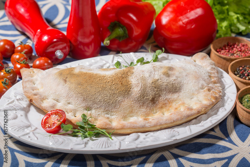freshly baked calzone on a decorative white plate with shell patterns