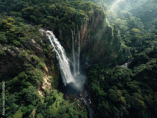 Majestic waterfall cascades amidst lush, green, forested cliffs in a natural landscape