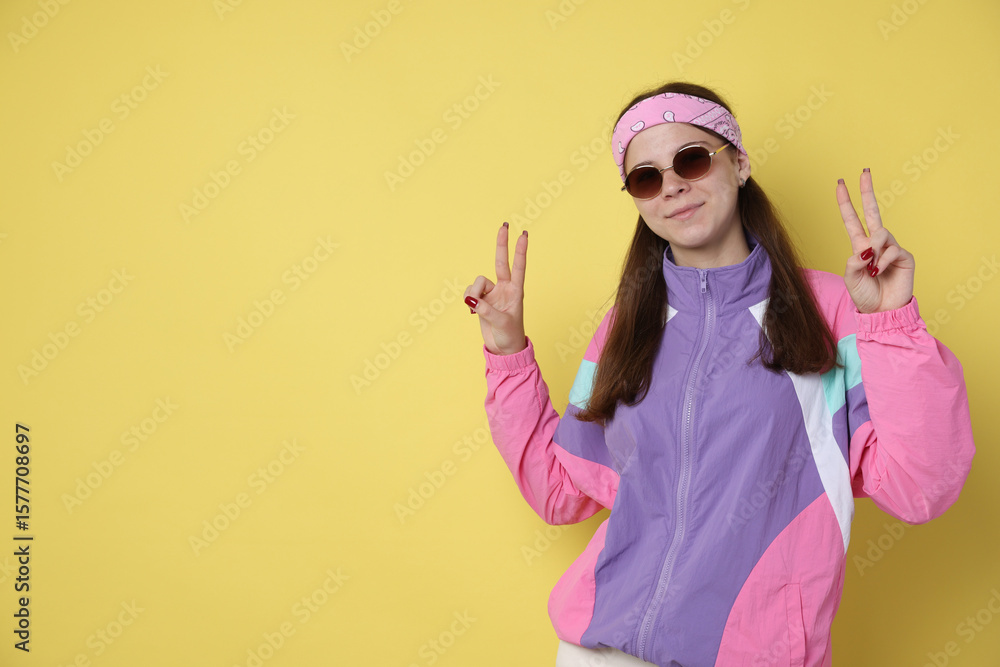 Teenage girl in sunglasses showing peace sign on yellow background, space for text Teenage girl in sunglasses showing peace sign on yellow background, space for text
