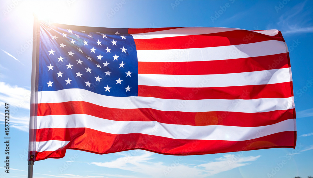 Fototapeta premium A close-up shot of the flag of United States waving with a sunny sky in background. The image represents national pride and patriotism