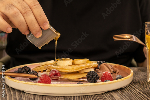 Maple Syrup Poured over Berry-topped Pancakes
