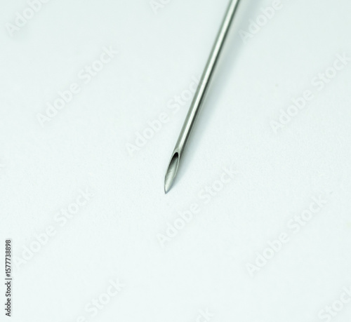 Close-up view of a standard hypodermic needle tip on a clean white background. Used for medical injections, vaccinations, and blood draws. Sharp stainless steel bevel clearly visible.