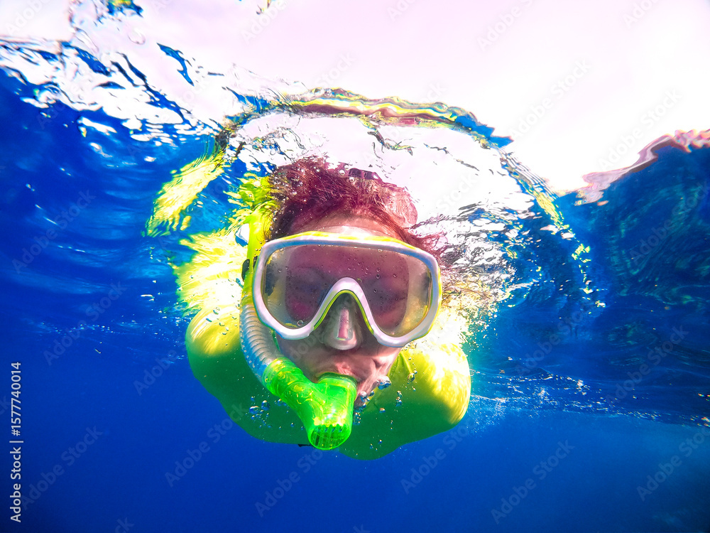 Naklejka premium Portrait of a woman in a mask with a snorkel floating underwater in the sea