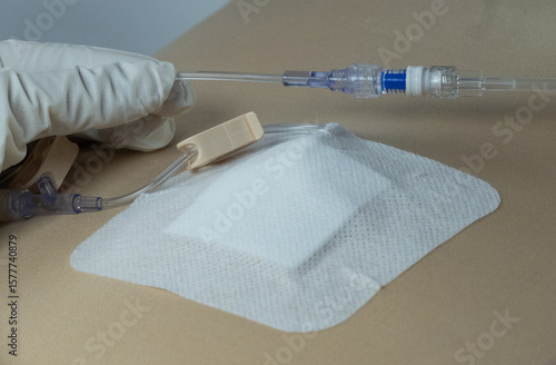 Foto Gripper (Huber) needle connected to IV tubing and non-return cap over a port-a-cath site, covered with opaque dressing