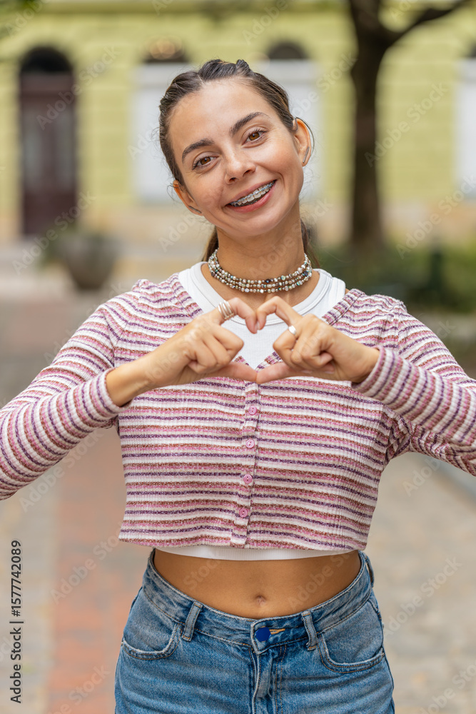 I love you. Caucasian woman makes symbol of love, showing heart sign to camera, express romantic feelings express sincere positive emotions. Charity, gratitude, donation. Outdoors in urban city street I love you. Caucasian woman makes symbol of love, showing heart sign to camera, express romantic feelings express sincere positive emotions. Charity, gratitude, donation. Outdoors in urban city street
