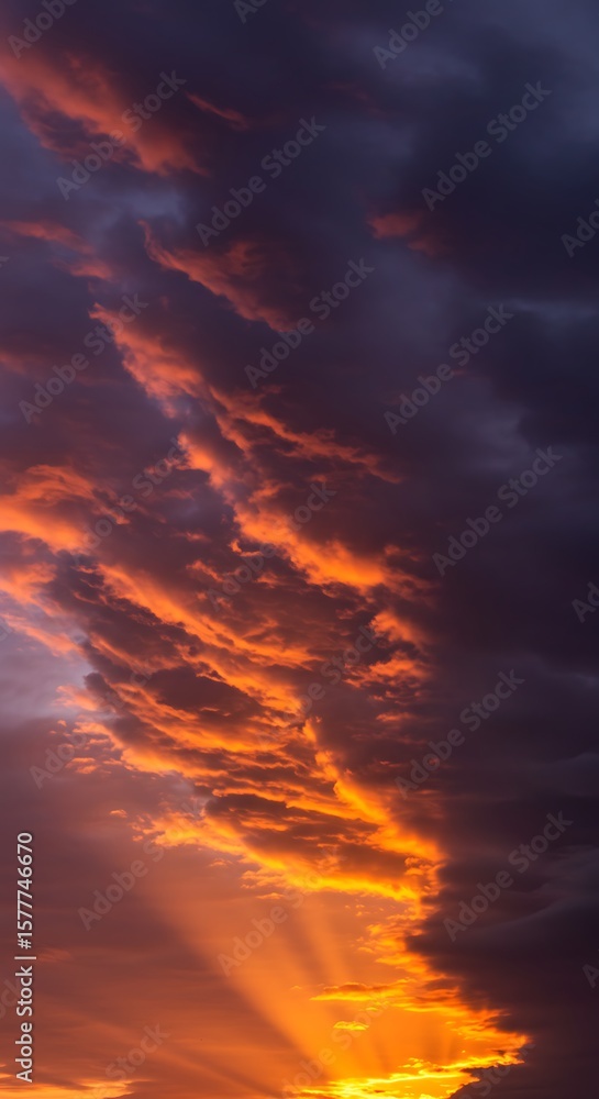 Fototapeta premium Fiery orange clouds at sunset with dark skies