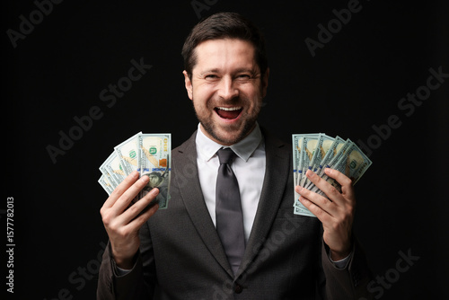 Fényképezés Happy greedy banker with dollar banknotes on black background