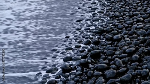 Ocean Waves Crashing on Black Pebble Beach: Dynamic Coastal Scene