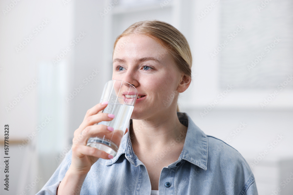 Young woman drinking water from glass at home Young woman drinking water from glass at home