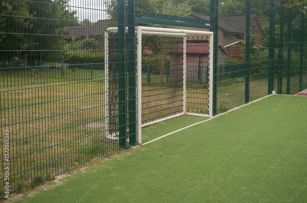 Fototapeta premium Empty soccer field with goal post and green synthetic turf