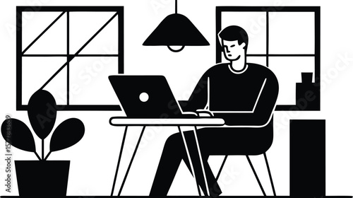 A man works diligently on his laptop at a desk in a room with windows
