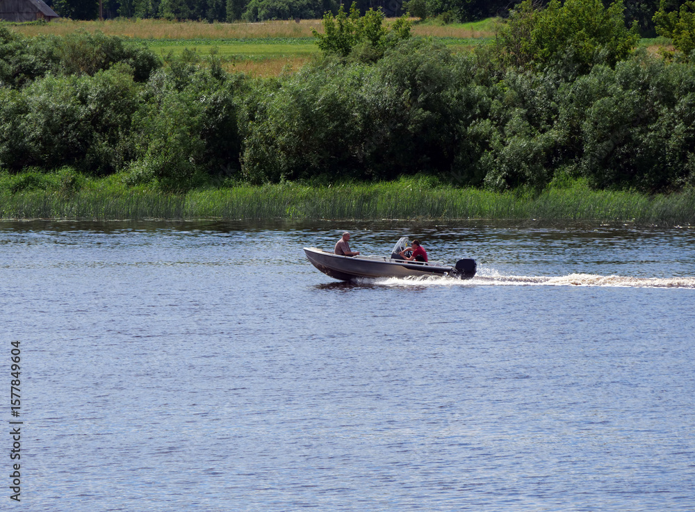 Obraz premium Small Motorboat with Two People Cruising on a Wide River. Summer Activity.