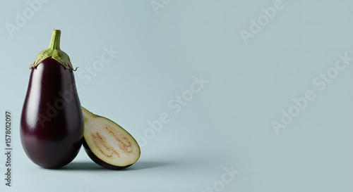 Fresh eggplant with one half sliced, set against a light pastel background, highlighting its glossy skin and creamy interior, perfect for healthy cooking and vegetarian dishes.