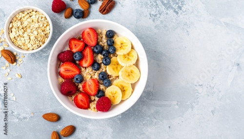 Top View of Oatmeal Bowl with Assorted Fresh Fruits and Almonds on Grey Table