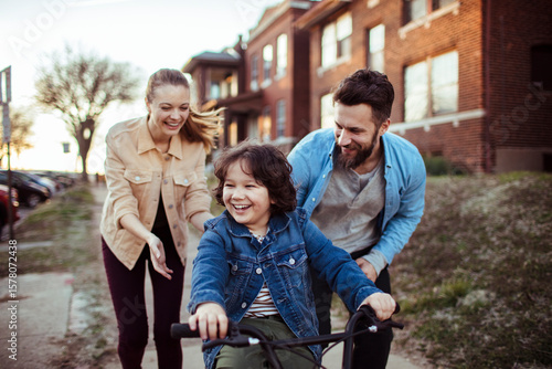 Parents teaching young son how to ride a bike outside