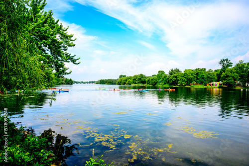 kayakers crossing a large pond on the toronto islands with green trees and blue sky room for text