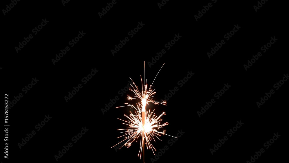 Obraz premium Close up shot of a single sparkler emitting bright sparks against a dark black background at night