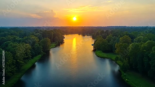 Aerial view of a serene river flowing through lush forest at breathtaking sunset
