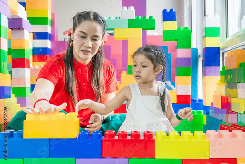 Mother teaching Asian daughter to build plastic model into different shapes according to imagination.
