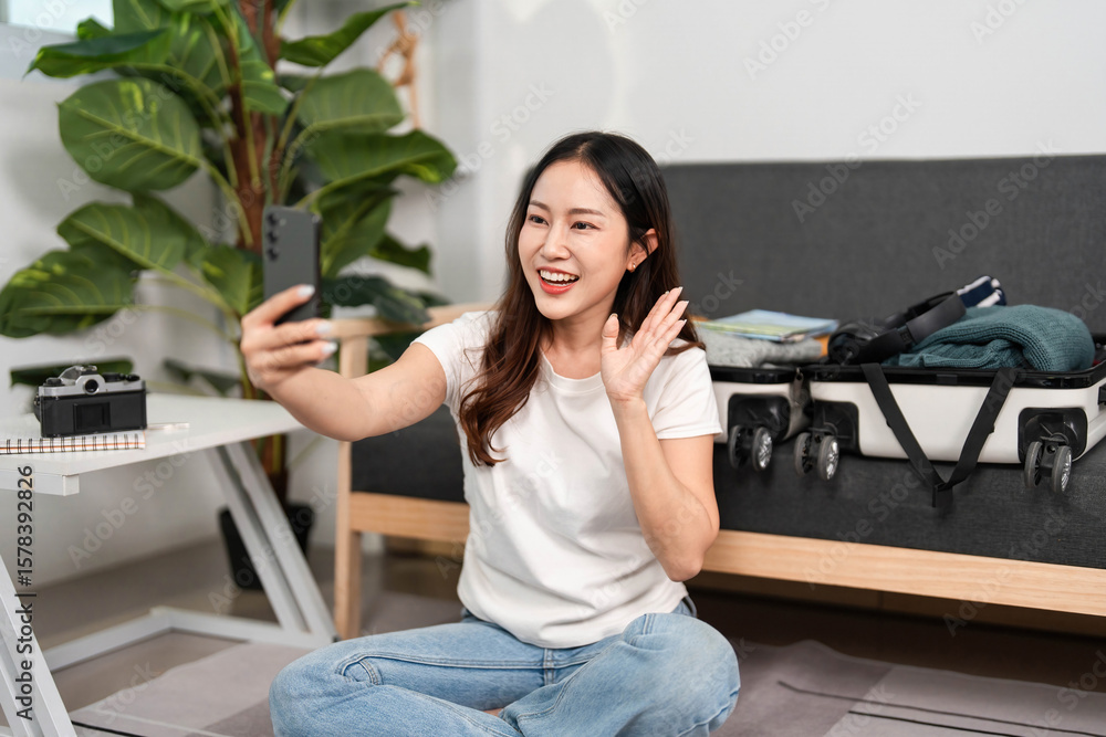 Joyful Travel Preparation. Young woman smiling while taking a selfie during her packing process. Joyful Travel Preparation. Young woman smiling while taking a selfie during her packing process.