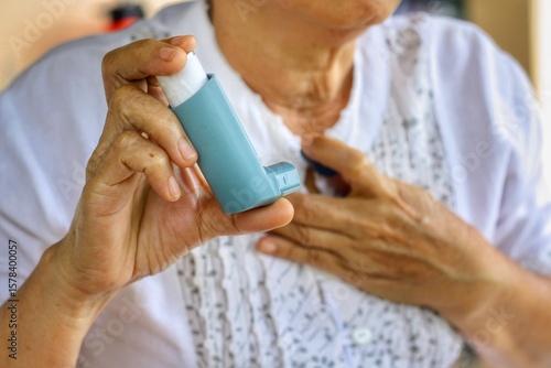 Elderly Female's hand holding inhaler with blurred background.Medication for relief bronchospasm or Dyspnea from asthma attack or allergy,that's an emergency condition.Healthcare and medical concept.