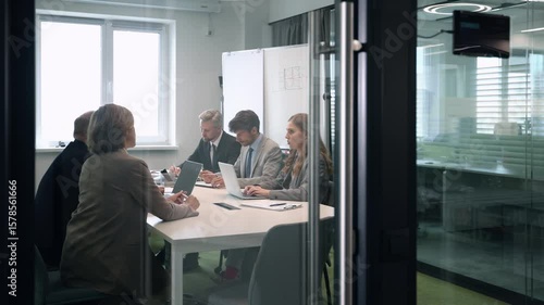 Business office with businesspeople, with blurred bokeh background, view from glass wall.