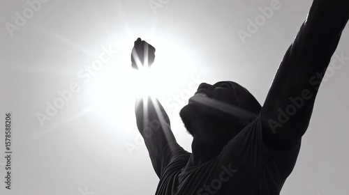 Un homme avec les bras levés célèbre sa victoire sous un rayon de soleil