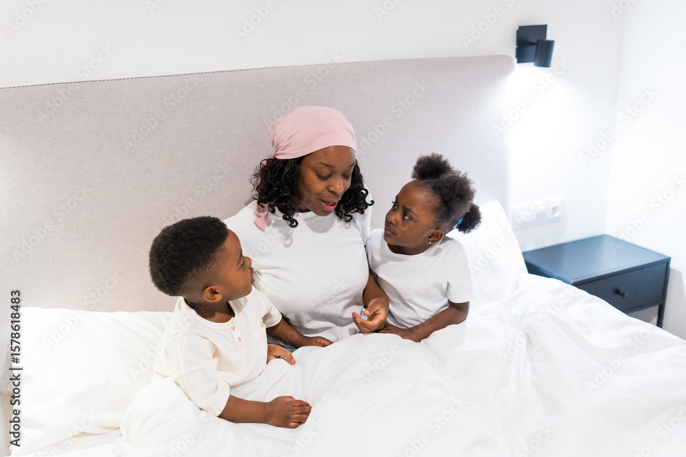 Obraz premium Mother with cancer talking to her children in bed, maintaining normality and family bonds